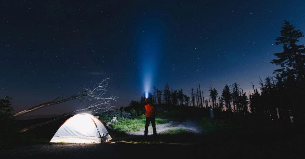 person camping holding a flashlight