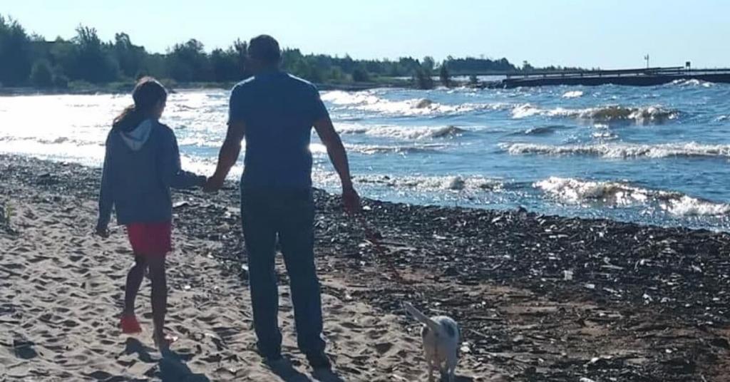 people walking on lake Michigan beach with their dog